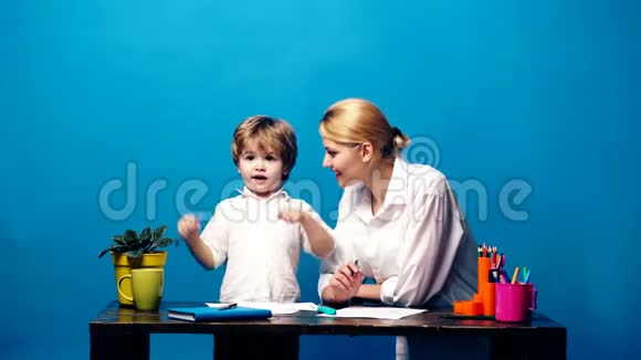年轻的女人带着一个用彩色铅笔在蓝色背景上画的小男孩妈妈和儿子用彩色画视频的预览图