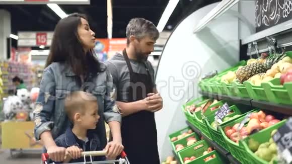 帅哥店员正在卖新鲜水果给有孩子的有魅力的年轻女人男人指着明亮视频的预览图