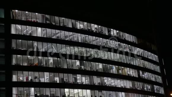 晚上大型办公楼有灯光的窗户人们完成这项工作从底部看视频的预览图