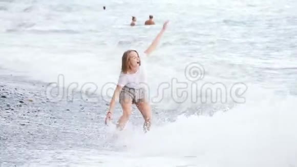 美丽的年轻女子玩着大海的浪花视频的预览图