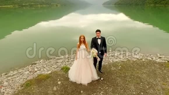 美丽而快乐的新娘和新郎在河岸上抛洒一束婚礼花视频的预览图