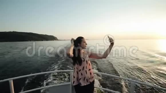 一个美丽的女孩站在船上鞠躬在风景优美的景色前自拍视频的预览图