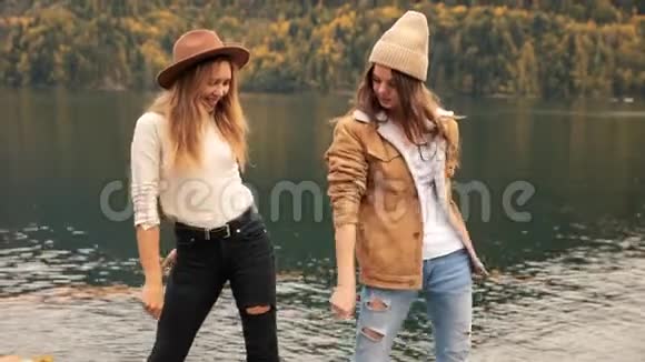 两个女孩在湖上的背景下在山上跳舞为博客而笑社交媒体旅游博客视频的预览图