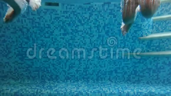 两个女孩手牵着手在游泳池里跳跃和在水下潜水的慢动作水下镜头气泡视频的预览图