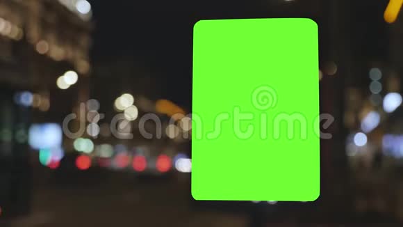 有绿色屏幕的广告牌位于一条繁忙的街道上汽车在晚上移动背景已经失去了焦点视频的预览图