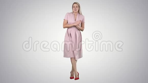 可爱的女孩穿着粉红色连衣裙与相机交谈在渐变背景上微笑视频的预览图
