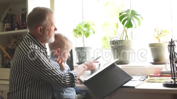 祖父和孙子在家沙发上爷爷和孩子们看老照片视频的预览图