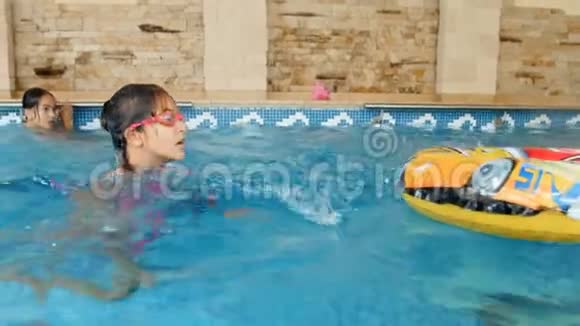 一家人带着孩子在室内游泳池游泳的快乐年轻家庭的4k镜头视频的预览图