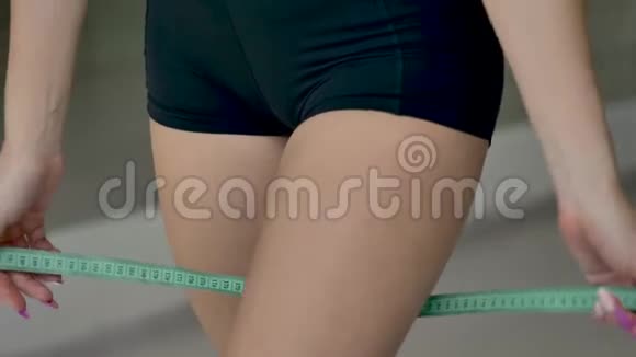 高加索运动女孩用测量带测量大腿的体积视频的预览图