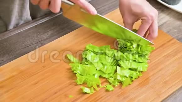 女性手的特写是用沙拉叶切一把刀用于在木切上做色拉素素菜视频的预览图
