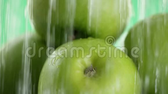 绿色的苹果然后水开始从不同喷流的顶部落下绿色的背景关闭视频的预览图