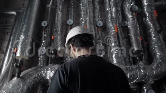 穿白色头盔的人在管道对面的锅炉里回到摄像机前视频的预览图