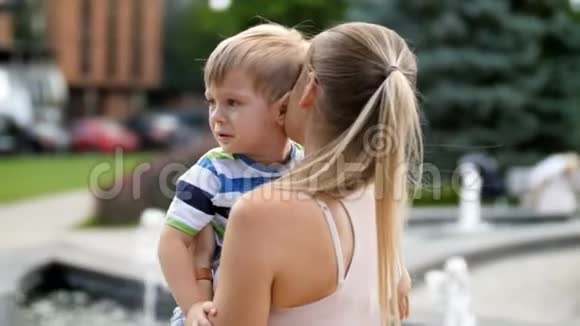 4k视频年轻母亲拥抱和抚摸她蹒跚学步的儿子在公园哭泣视频的预览图