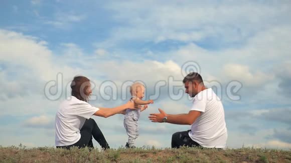 幸福的一家人坐在绿草上家庭在户外玩得很开心快乐的年轻家庭在一起视频的预览图
