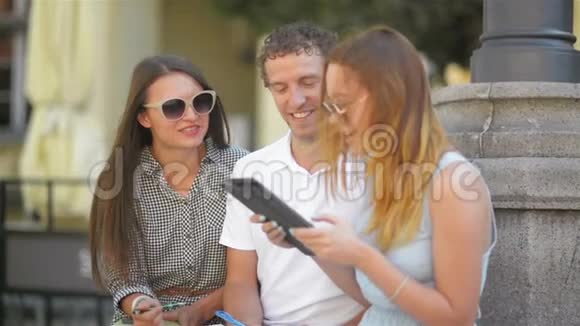 两个女孩和一个男人有笔记笔和平板花时间在外面三个微笑学生的户外画像视频的预览图