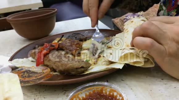 在咖啡馆或餐馆用叉子吃卢拉串肉的人的手视频的预览图
