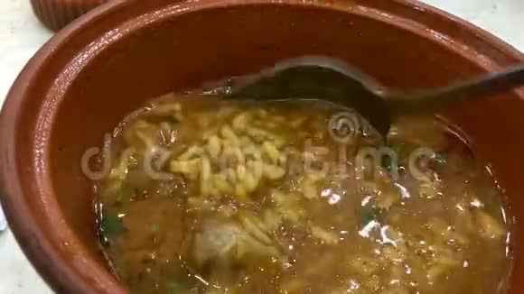 辣味米饭和羊肉卡其索汤与金属勺子混合在粘土碗中视频的预览图