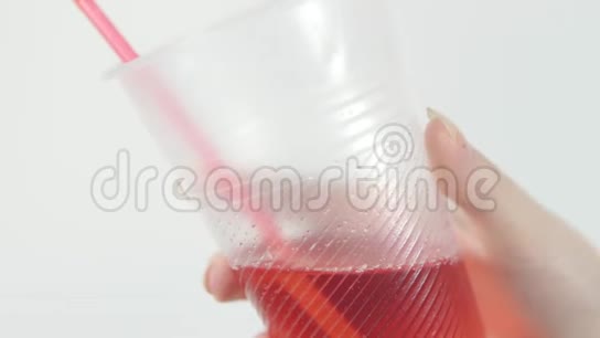 一个女人把一个塑料瓶里的红色水果饮料倒入玻璃杯里视频的预览图