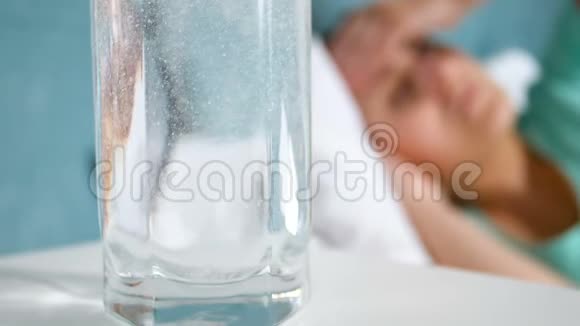 特写慢镜头头痛的女人躺在床上用阿司匹林喝一杯水视频的预览图