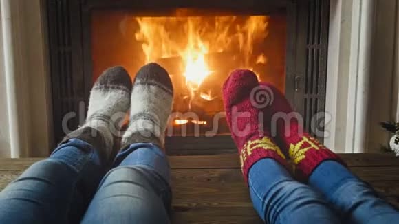 一对浪漫情侣穿着羊毛袜子躺在燃烧的壁炉旁的特写镜头视频的预览图