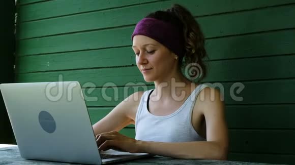 微笑商务女性旅游自由职业者在夏天的户外对着绿色的墙在笔记本电脑上打字视频的预览图