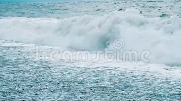巨浪在海上的风暴中拍打着卵石慢动作视频的预览图