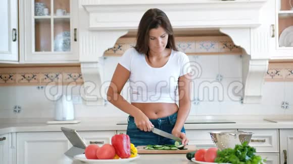有魅力的女人用刀切鲜黄瓜准备厨房的有机沙拉视频的预览图