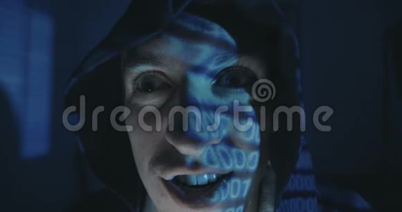 关闭疯狂黑客程序员在引擎盖与二进制代码反射在他的脸在黑暗的房间晚上肖像视频的预览图