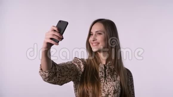 年轻的美女在智能手机上自拍交流理念白色背景视频的预览图