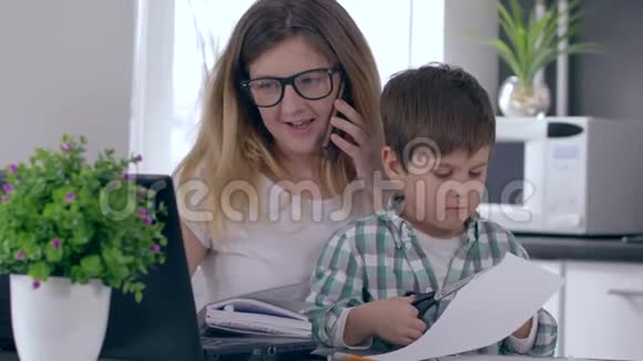 单身母亲在家工作用电脑打电话照顾儿子视频的预览图