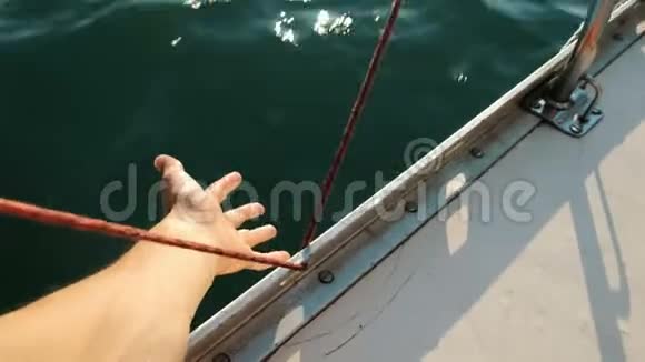 在游艇特写镜头中男性的手伸向海浪视频的预览图