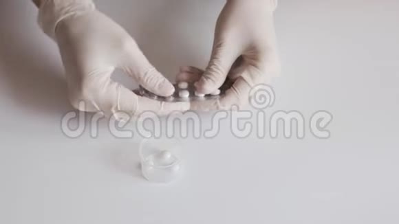 一位戴着白色乳胶手套的护士将药片从白色桌子上的水泡里挤出来视频的预览图