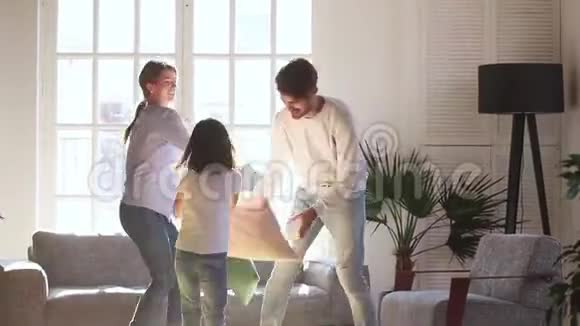 快乐的爸爸妈妈和小女儿打枕头战视频的预览图