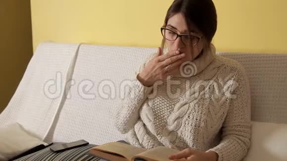 一个穿着白色毛衣的年轻女孩戴着眼镜在家里看着一本书打着电话一个女孩在说话视频的预览图