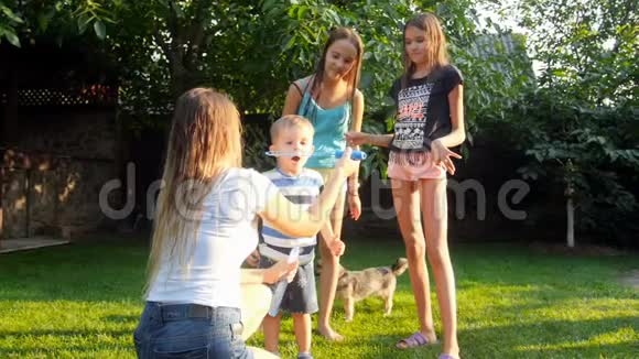 与母亲和姐妹一起学习吹肥皂泡的可爱学步男孩慢镜头视频的预览图