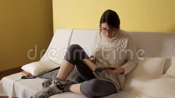 一个穿着白色毛衣的小女孩在一个冬天的晚上戴着眼镜在家看书心烦意乱书晚上好女孩视频的预览图