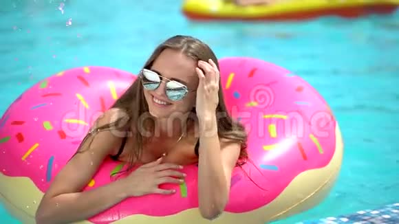 夏天美丽的年轻女子比基尼女郎在泳池度假夏季派对酒店的洒满甜甜圈中放松视频的预览图