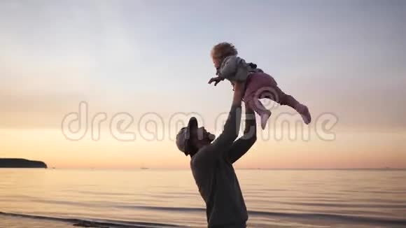 年轻的父亲和小女儿在沙滩上玩耍拥抱和欢笑呕吐视频的预览图