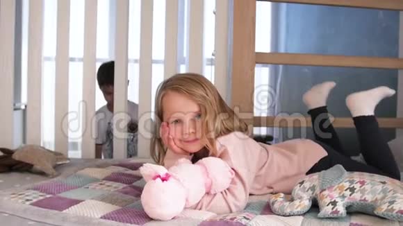 快乐的孩子在白色的卧室里玩小男孩小女孩哥哥姐姐穿着睡衣在床上玩家庭视频的预览图
