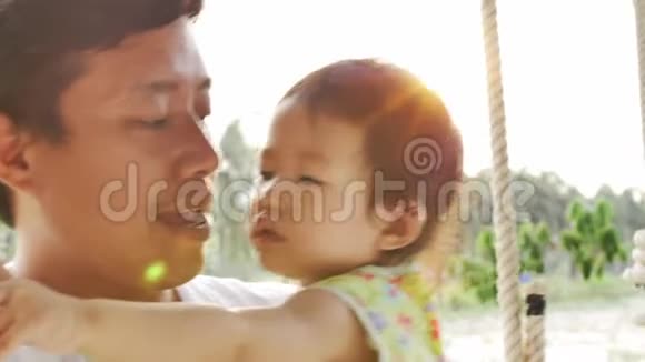 年轻父亲和他的小女儿在秋千上玩耍的肖像视频的预览图
