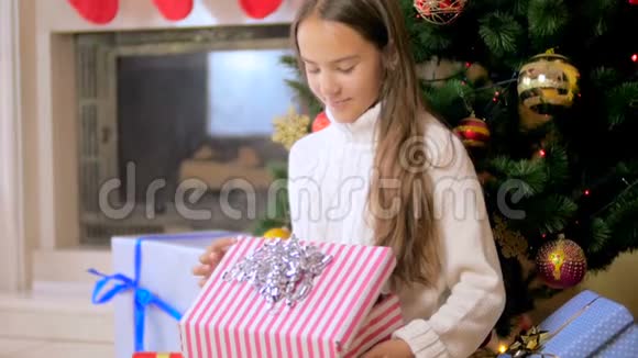 美丽的黑发女孩带着灰色小猫走出圣诞礼盒的慢动作视频视频的预览图