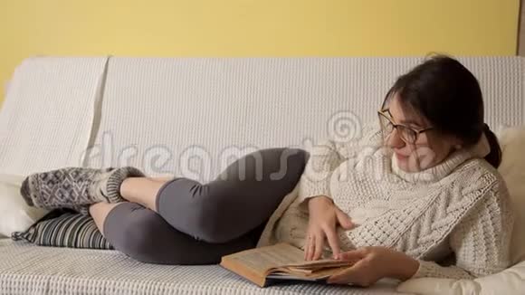 一个穿着白色毛衣的年轻女孩在一个冬天的晚上戴着眼镜在家看书想睡觉这本书视频的预览图