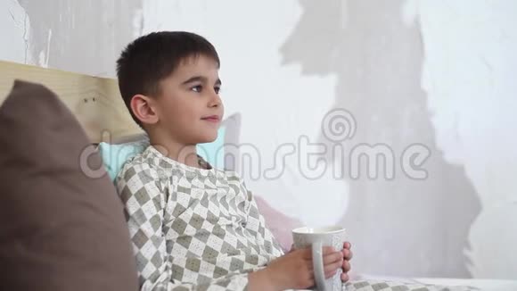 小男孩坐在床上喝杯子里的茶高清高清视频的预览图