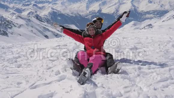 在山脉中一对快乐的滑雪者微笑和举起武器的画像视频的预览图