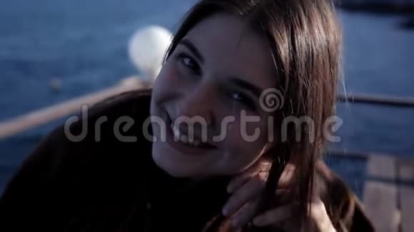 坐在海边的小女孩微笑着为照相机摆姿势视频的预览图