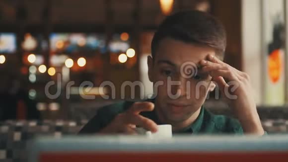 一个年轻的商人坐在咖啡馆的桌子旁看着一台笔记本电脑看着过路人成功人士视频的预览图