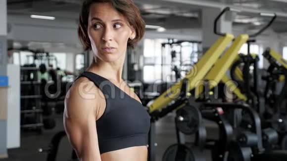 运动成熟的女人正在健身房用哑铃做二头肌运动视频的预览图