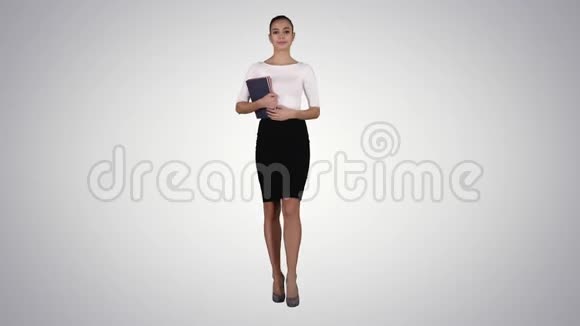 美丽的年轻女子带着笔记本走在梯度背景上视频的预览图