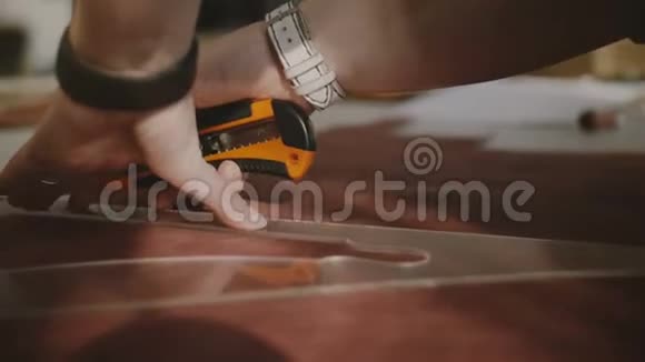 用刀和三角曲线尺在大车间工作台上用皮革切割出的女性手的特写镜头视频的预览图