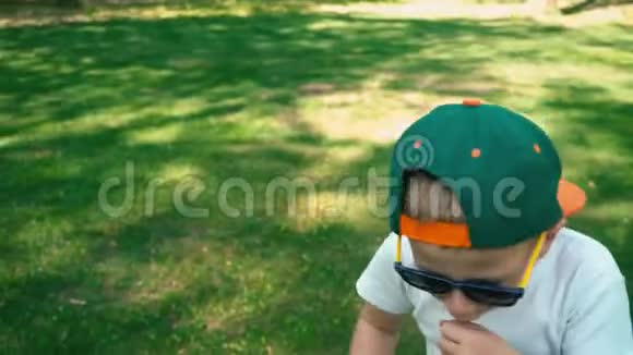 一个5岁的小男孩戴着太阳镜在夏天的公园里咳嗽孩子的真实情绪视频的预览图